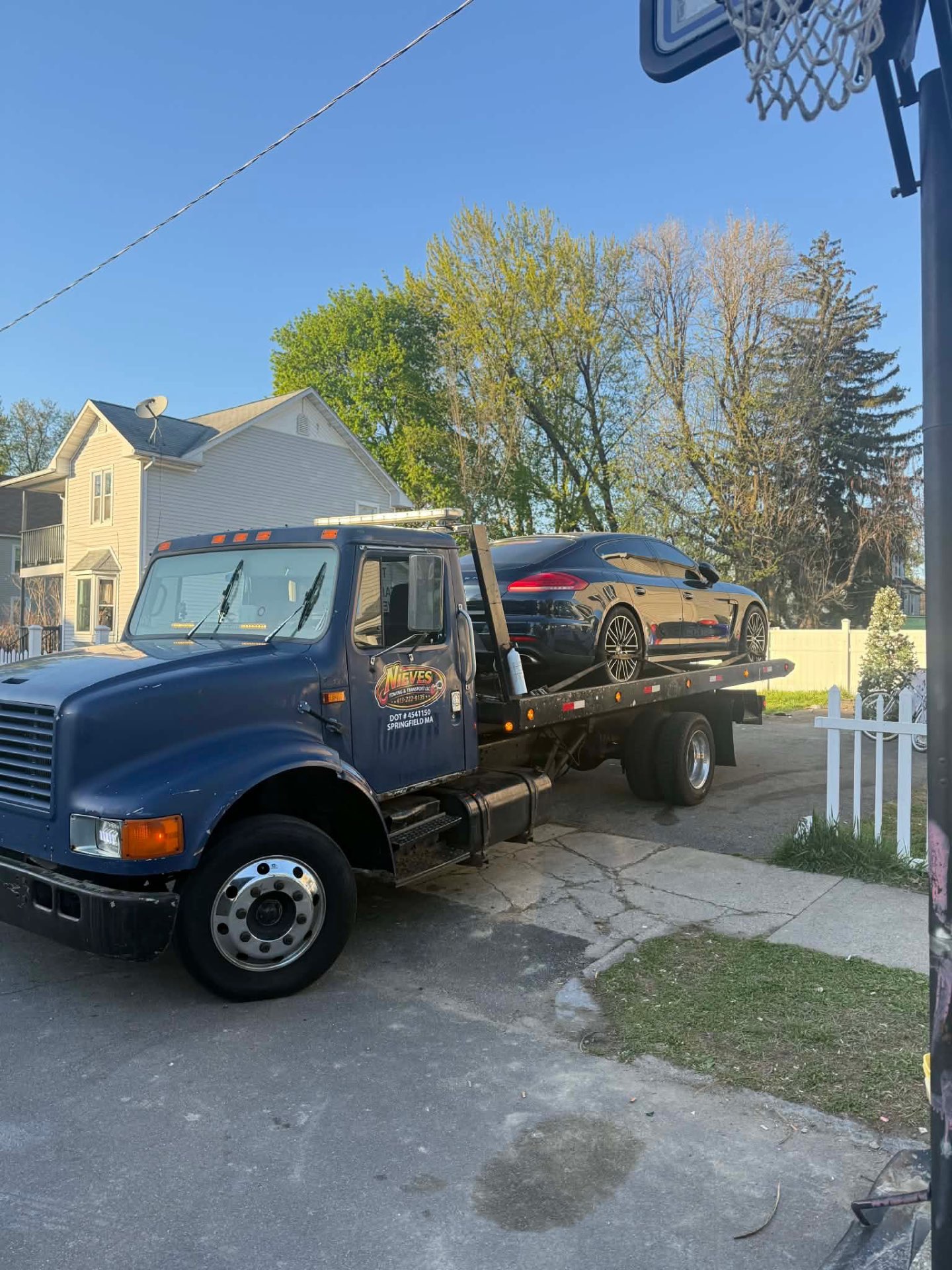Nieves Towing flatbed transporting a black Porsche Panamera