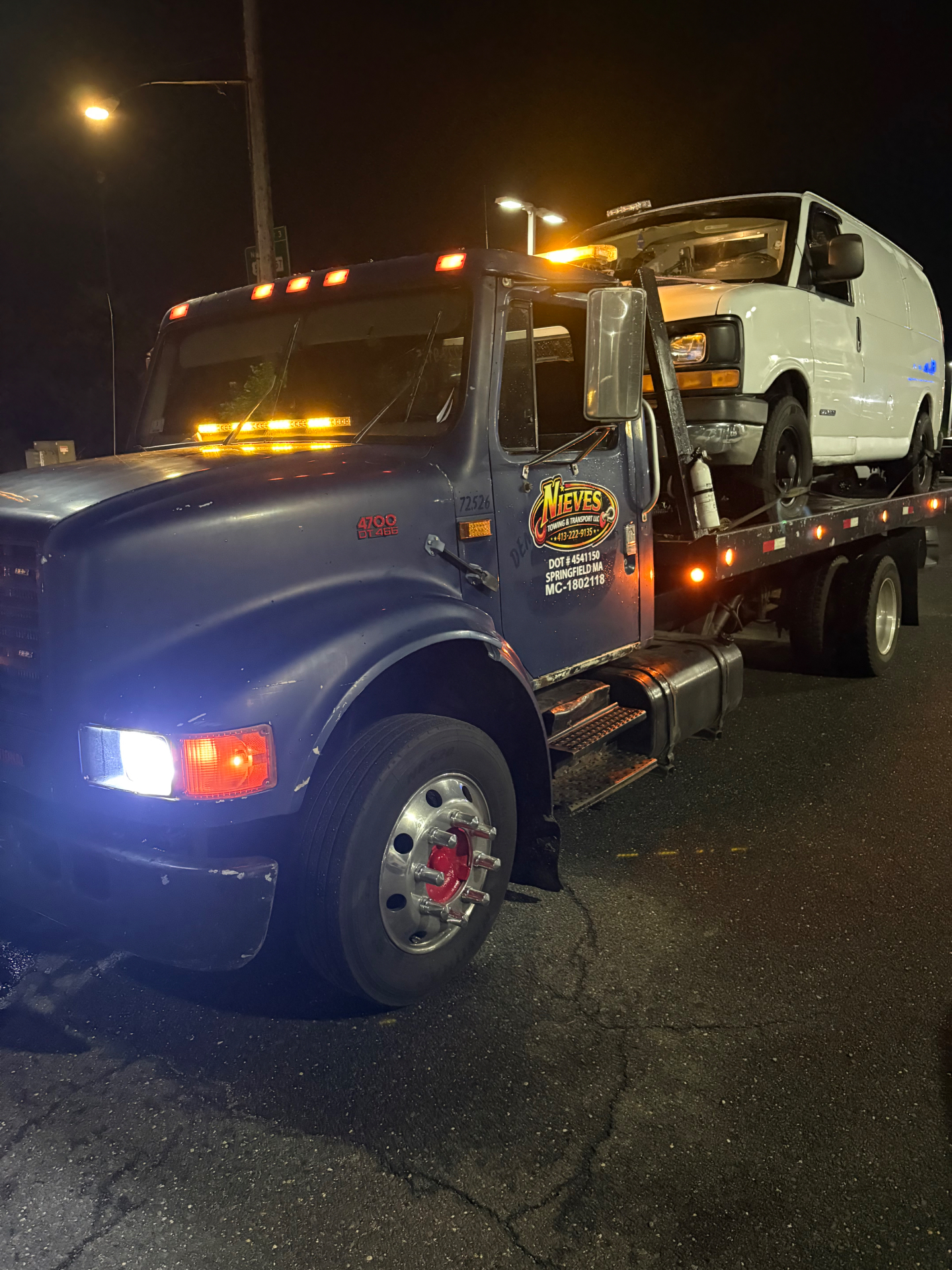 Nieves Towing flatbed tow truck loading a van at night in Springfield, MA